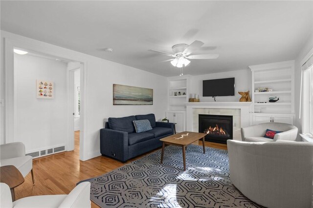 19 Woodsia Rd, Narragansett, RI 02874 - living room featuring a lit fireplace, light wood-style floors, a ceiling fan, built in shelves, and baseboards