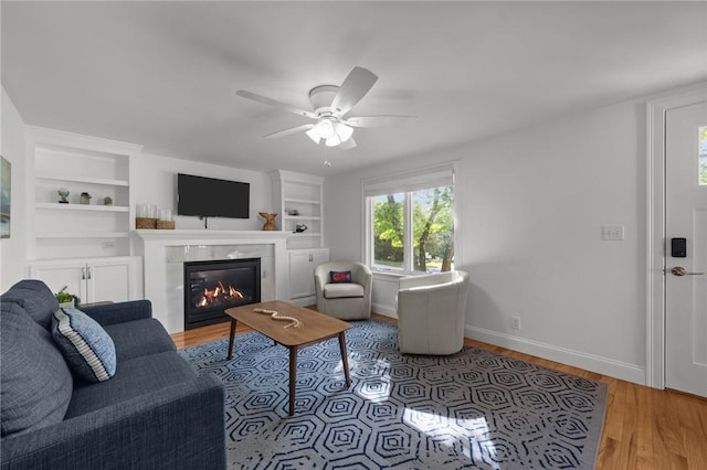 19 Woodsia Rd, Narragansett, RI 02874 - living area featuring a tile fireplace, wood finished floors, ceiling fan, built in features, and baseboards