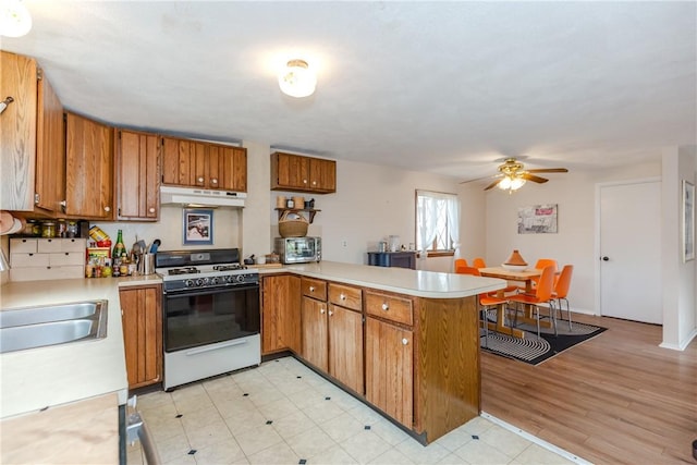 339 Beverage Hill Ave, Pawtucket, RI 02861 - kitchen with white range with gas cooktop, brown cabinets, a peninsula, light countertops, and under cabinet range hood