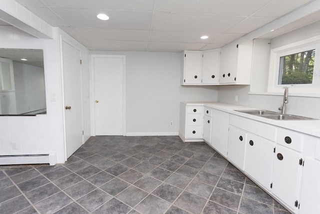 38 Williams Rd, Smithfield, RI 02917 - kitchen featuring a sink, a paneled ceiling, a baseboard heating unit, white cabinetry, and light countertops