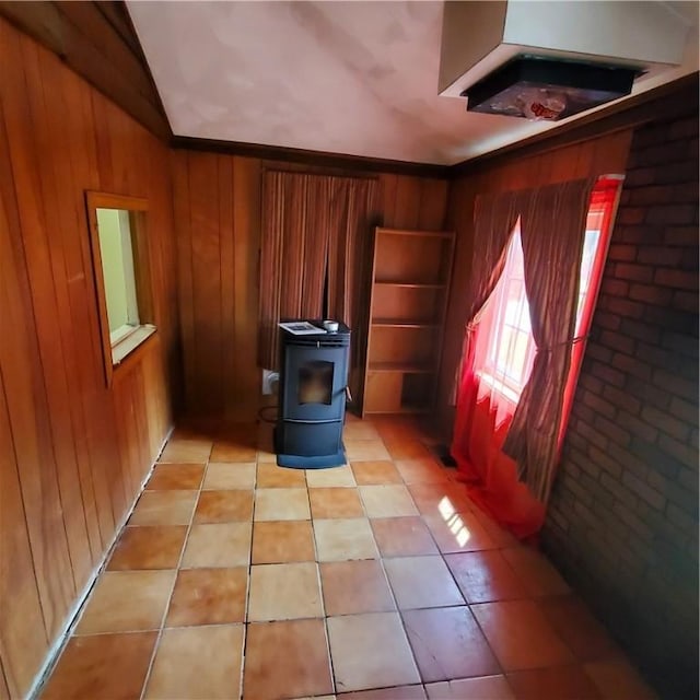199 Plainfield Pike, Scituate, RI 02857 - empty room with lofted ceiling, wooden walls, a wood stove, and light tile patterned flooring
