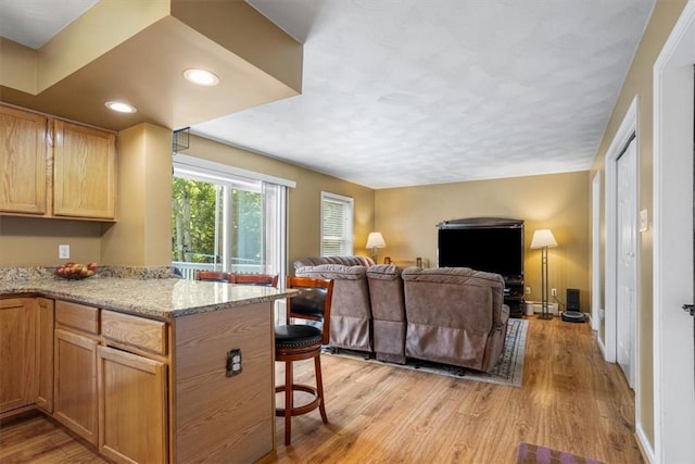 46 Lincoln Dr, Johnston, RI 02919 - kitchen featuring a kitchen bar, light wood-style flooring, open floor plan, light stone countertops, and a peninsula