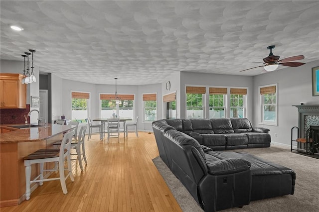 510 Westmoreland Ln, North Kingstown, RI 02874 - living room featuring ceiling fan, light wood-type flooring, baseboards, a textured ceiling, and a fireplace with flush hearth
