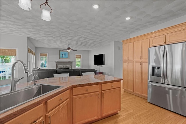 510 Westmoreland Ln, North Kingstown, RI 02874 - kitchen with stainless steel fridge, a sink, ceiling fan, light wood-style flooring, and a fireplace