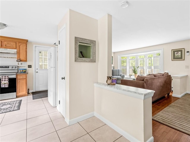 860 Centerville Rd, Warwick, RI 02886 - kitchen with stainless steel electric stove, freestanding refrigerator, under cabinet range hood, and light countertops