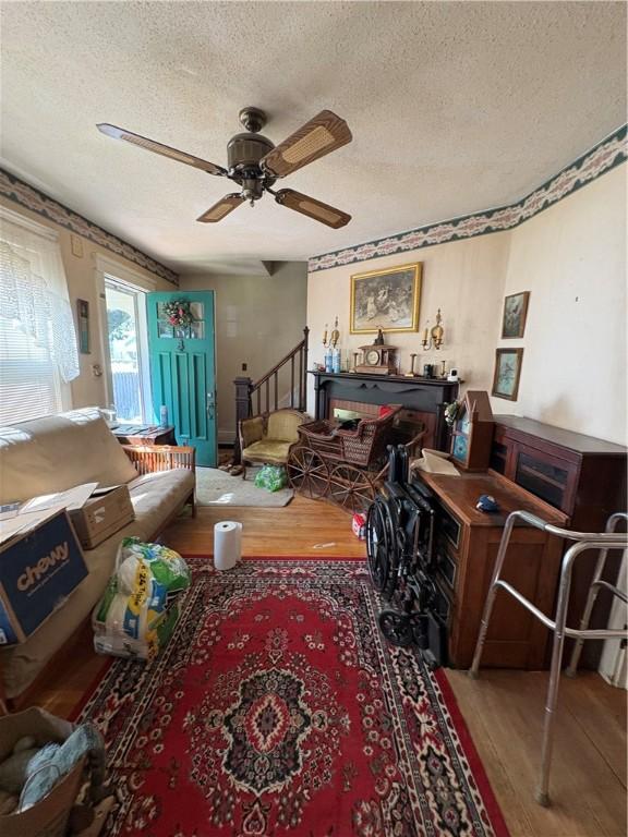 202 Jenckes St, Woonsocket, RI 02895 - living room featuring a textured ceiling, wood finished floors, ceiling fan, and stairway