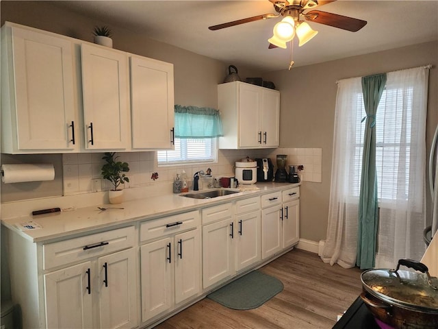 27 Unit St, Providence, RI 02909 - kitchen featuring a sink, backsplash, white cabinets, light countertops, and light wood-style flooring