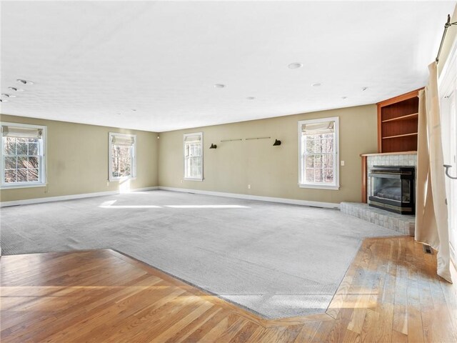 44 Azalea Ave, Exeter, RI 02822 - unfurnished living room with baseboards, a glass covered fireplace, built in features, carpet floors, and wood finished floors