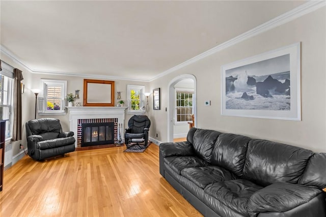 44 Felsmere Ave, Pawtucket, RI 02861 - living room featuring a brick fireplace, crown molding, light wood finished floors, arched walkways, and baseboards