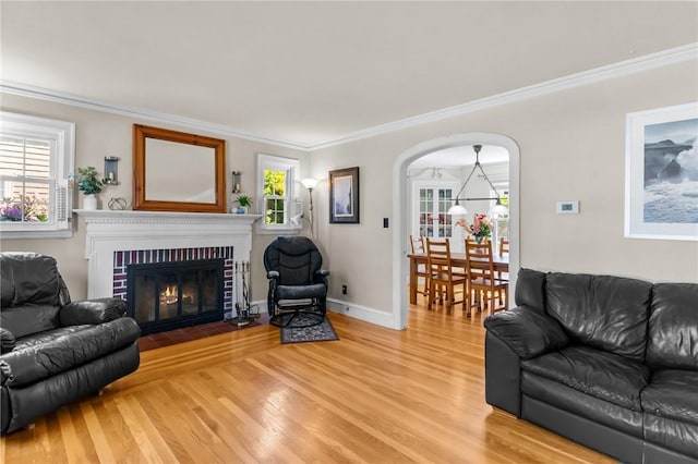 44 Felsmere Ave, Pawtucket, RI 02861 - living room featuring light wood-type flooring, ornamental molding, arched walkways, a brick fireplace, and baseboards