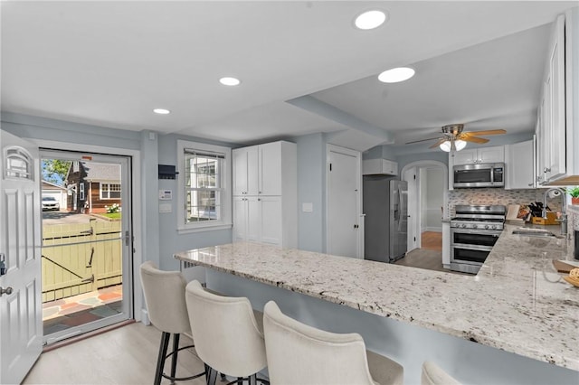 44 Felsmere Ave, Pawtucket, RI 02861 - kitchen with stainless steel appliances, a sink, light stone countertops, a peninsula, and white cabinetry