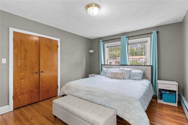 299 Buttonwoods Ave, Warwick, RI 02886 - bedroom featuring wood finished floors, a baseboard heating unit, a closet, and baseboards