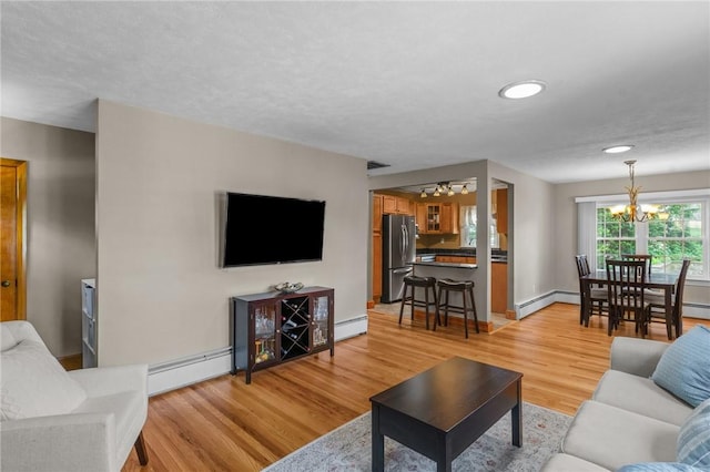 299 Buttonwoods Ave, Warwick, RI 02886 - living area featuring a chandelier, baseboard heating, light wood finished floors, and baseboards