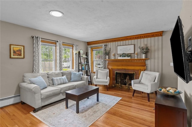 299 Buttonwoods Ave, Warwick, RI 02886 - living room featuring baseboard heating, light wood-style flooring, a brick fireplace, and baseboards