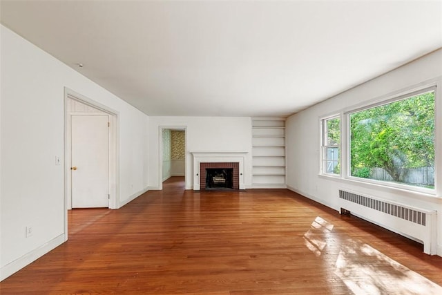 37 Beaumont St, East Providence, RI 02916 - unfurnished living room with radiator, built in features, a brick fireplace, and wood finished floors