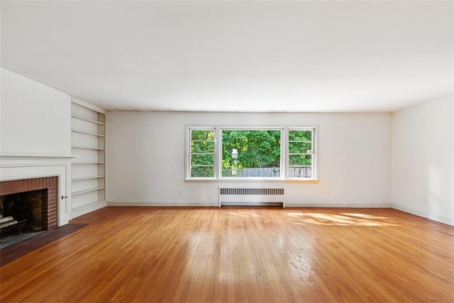 37 Beaumont St, East Providence, RI 02916 - unfurnished living room with radiator heating unit, hardwood / wood-style flooring, a brick fireplace, built in features, and baseboards
