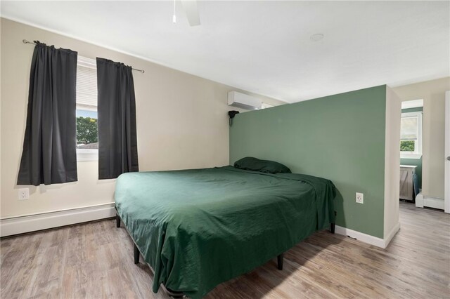 73 Vineyard Ave, Cumberland, RI 02864 - bedroom featuring an AC wall unit, multiple windows, a baseboard radiator, and wood finished floors