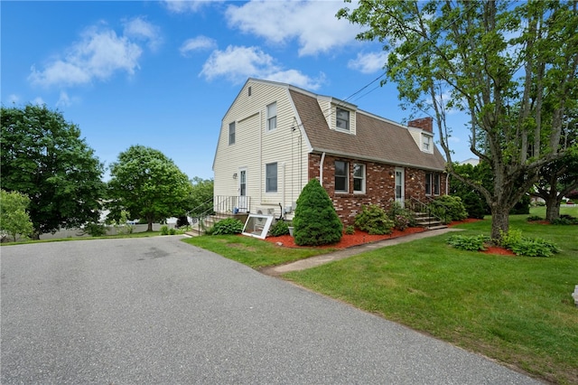 73 Vineyard Ave, Cumberland, RI 02864 - view of side of property featuring a chimney, a lawn, brick siding, a gambrel roof, and roof with shingles