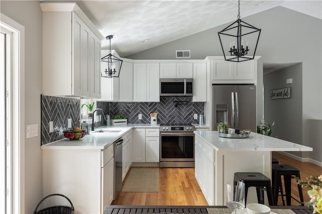 128 Old Quarry Rd, Glocester, RI 02857 - kitchen with a chandelier, stainless steel appliances, a sink, vaulted ceiling, and light wood-type flooring
