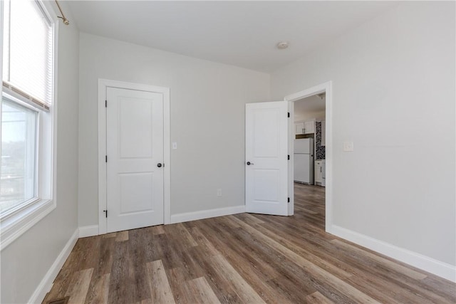 214 Silver Spring St, Providence, RI 02904 - unfurnished bedroom featuring freestanding refrigerator, wood finished floors, baseboards, and multiple windows