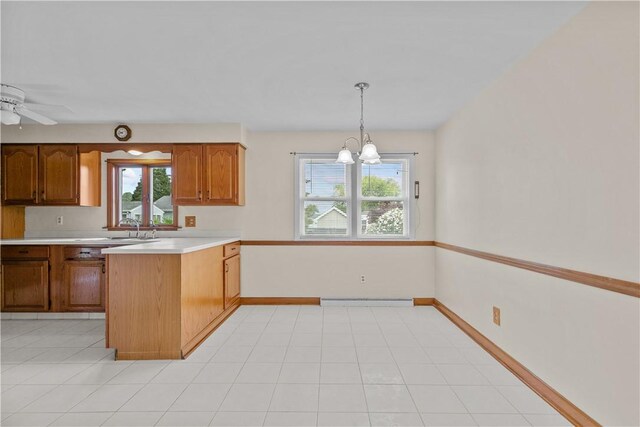 174 Russell Dr, Tiverton, RI 02878 - kitchen featuring light countertops, a peninsula, brown cabinetry, decorative light fixtures, and a chandelier