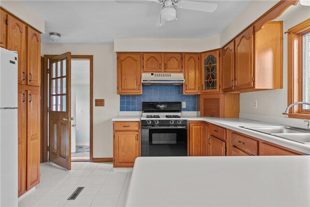 174 Russell Dr, Tiverton, RI 02878 - kitchen featuring gas stove, freestanding refrigerator, under cabinet range hood, decorative backsplash, and brown cabinetry