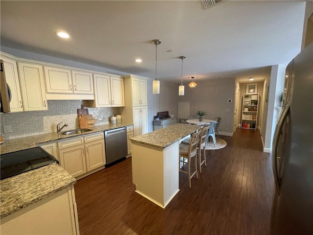 60 Saw Mill Dr Unit 303, North Kingstown, RI 02852 - kitchen featuring appliances with stainless steel finishes, a sink, a kitchen breakfast bar, dark wood-type flooring, and light stone countertops