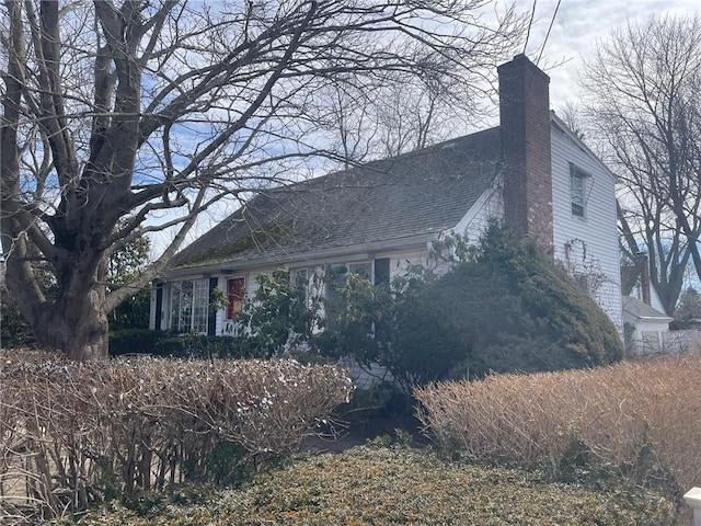137 Bayview Ave, North Kingstown, RI 02852 - view of home's exterior featuring a chimney and a shingled roof