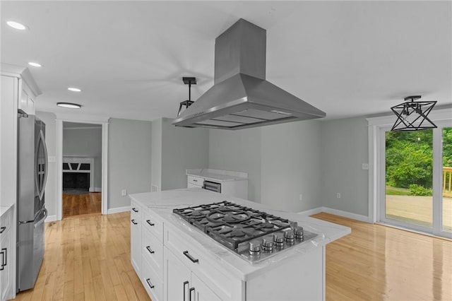 529 Rocky Hill Rd, Scituate, RI 02857 - kitchen with island range hood, stainless steel appliances, light wood-style flooring, white cabinetry, and light stone countertops