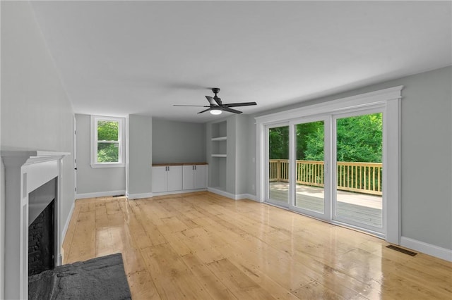 529 Rocky Hill Rd, Scituate, RI 02857 - unfurnished living room with light wood-style flooring, a ceiling fan, a fireplace, built in shelves, and baseboards