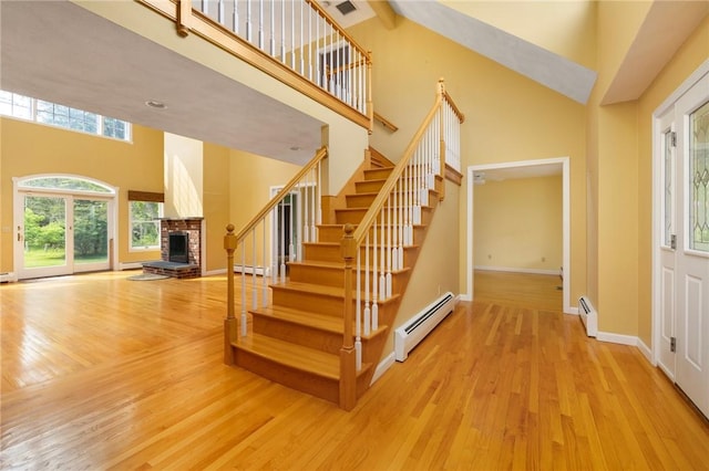 30 Walden Way S, Kingstown, RI 02879 - entryway featuring a baseboard heating unit, high vaulted ceiling, a brick fireplace, wood finished floors, and stairs