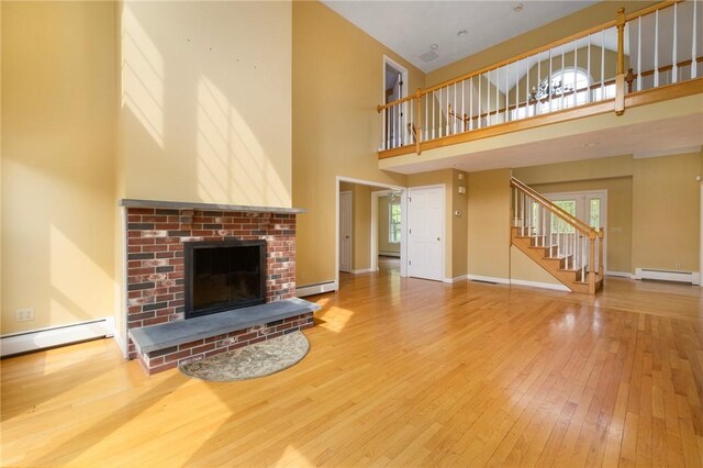 30 Walden Way S, Kingstown, RI 02879 - unfurnished living room with a baseboard heating unit, wood-type flooring, a high ceiling, a baseboard radiator, and plenty of natural light