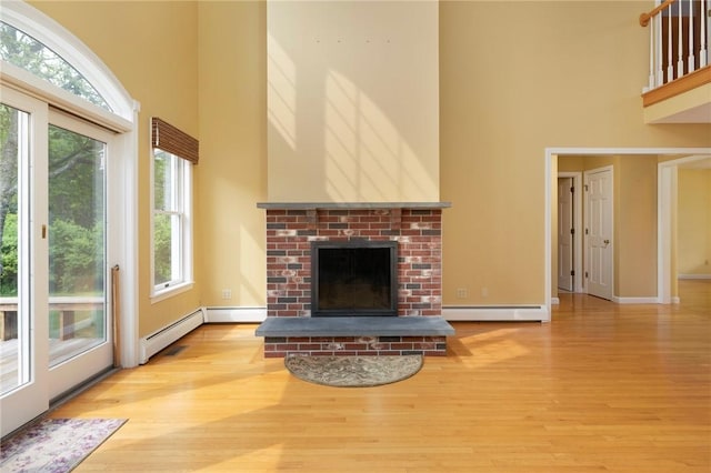 30 Walden Way S, Kingstown, RI 02879 - unfurnished living room with a towering ceiling, a brick fireplace, baseboard heating, wood finished floors, and healthy amount of natural light