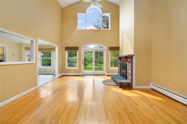 30 Walden Way S, Kingstown, RI 02879 - unfurnished living room with a baseboard radiator, wood finished floors, plenty of natural light, high vaulted ceiling, and a brick fireplace