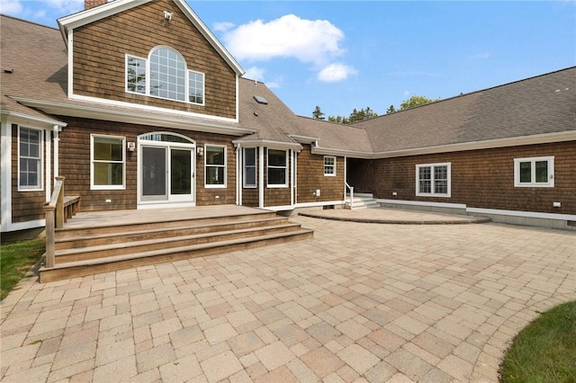 30 Walden Way S, Kingstown, RI 02879 - back of property with a patio area, roof with shingles, and a chimney