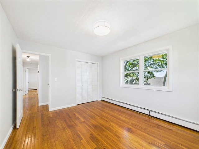 5 Conca St, North Providence, RI 02904 - unfurnished bedroom featuring a baseboard heating unit, wood-type flooring, a closet, and baseboards