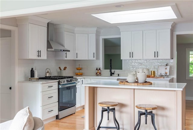 24 W Knollwood Cir, North Kingstown, RI 02852 - kitchen with wall chimney range hood, stainless steel range with gas cooktop, a skylight, and decorative backsplash