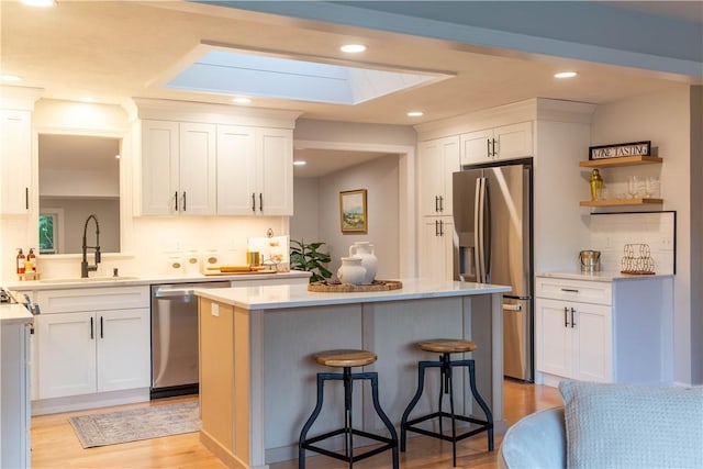 24 W Knollwood Cir, North Kingstown, RI 02852 - kitchen with stainless steel appliances, a skylight, a sink, a kitchen island, and light countertops