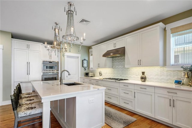 171 Leeshore Ln, Tiverton, RI 02878 - kitchen featuring under cabinet range hood, a sink, gas cooktop, a chandelier, and backsplash