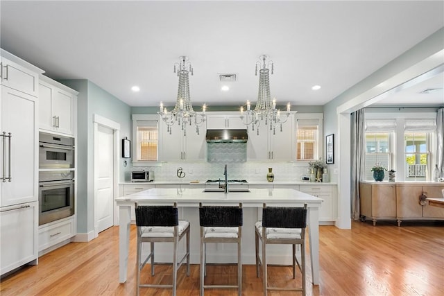 171 Leeshore Ln, Tiverton, RI 02878 - kitchen with a chandelier, under cabinet range hood, light countertops, decorative backsplash, and a kitchen island with sink