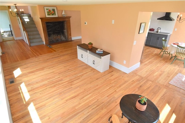 259 Green Hill Beach Rd, South Kingstown, RI 02879 - living room with light wood-style floors, baseboards, stairway, a fireplace with flush hearth, and a chandelier