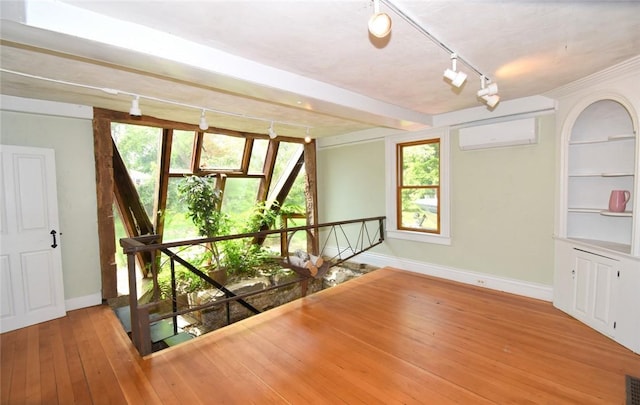 259 Green Hill Beach Rd, South Kingstown, RI 02879 - empty room featuring track lighting, a wall unit AC, baseboards, wood-type flooring, and healthy amount of natural light