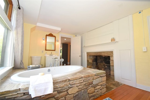 259 Green Hill Beach Rd, South Kingstown, RI 02879 - bathroom featuring a bath, vanity, a fireplace, wood finished floors, and toilet