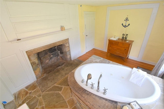 259 Green Hill Beach Rd, South Kingstown, RI 02879 - bathroom with a whirlpool tub, a fireplace with flush hearth, baseboards, and wood finished floors