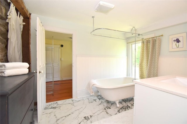 259 Green Hill Beach Rd, South Kingstown, RI 02879 - bathroom with wainscoting, a freestanding tub, vanity, a shower with shower curtain, and marble finish floors