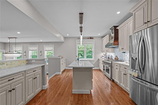 40 Oakbrook Ct, East Greenwich, RI 02818 - kitchen featuring appliances with stainless steel finishes, wall chimney exhaust hood, a sink, light countertops, and light wood-type flooring
