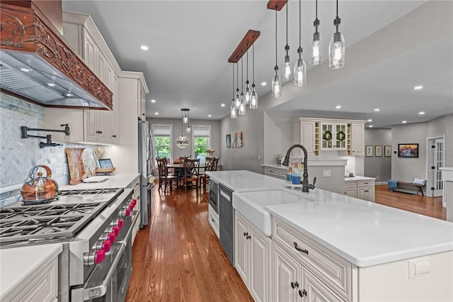 40 Oakbrook Ct, East Greenwich, RI 02818 - kitchen with wall chimney range hood, stainless steel appliances, a sink, wood finished floors, and light countertops