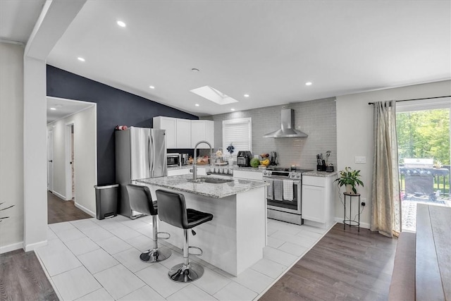 202 Hartford Pike, Foster, RI 02825 - kitchen with stainless steel appliances, a sink, wall chimney exhaust hood, a skylight, and white cabinetry