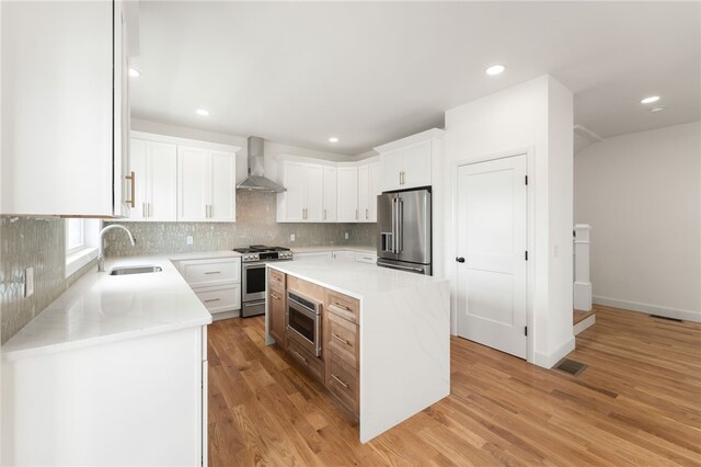 41 Burnett Rd, Warwick, RI 02889 - kitchen featuring stainless steel appliances, a sink, wall chimney exhaust hood, tasteful backsplash, and light wood-type flooring
