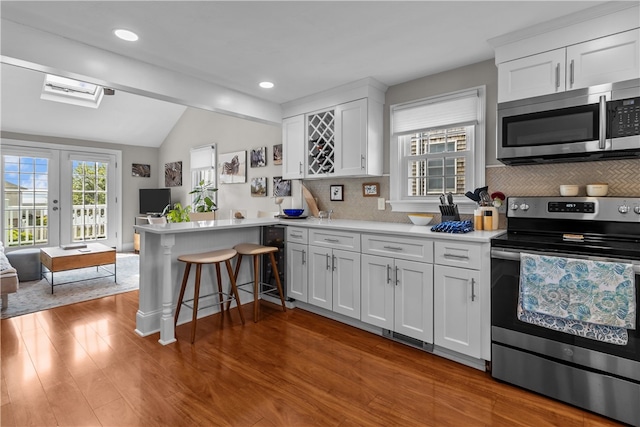 37 Brownell St, Warren, RI 02885 - kitchen featuring stainless steel appliances, a peninsula, vaulted ceiling, wine cooler, and backsplash